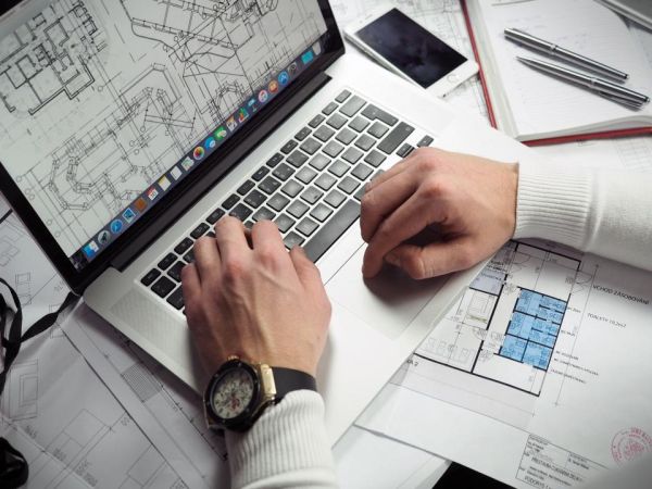 Workspace with laptop and planning documents used to illustrate website maintenance work